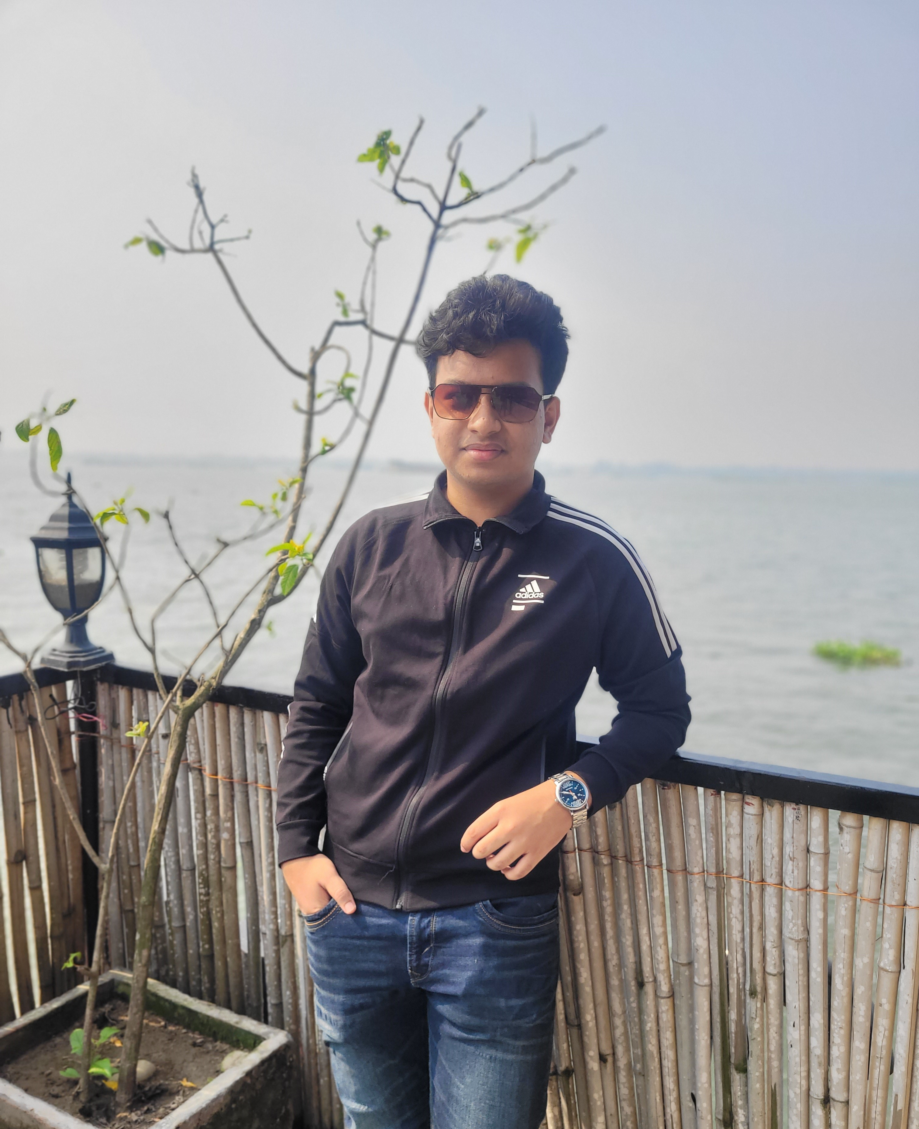 A man in a black jacket and sunglass posing with a smile